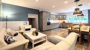 A modern living room with a sofa, coffee table, and dining area with a table and chairs. - Spacious holiday apartment with sauna, Kolobrzeg (Kolobrzeg)