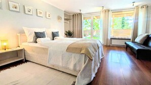 A bedroom with a large bed, a bedside table, a window with curtains, and a view of greenery outside. - Spacious holiday apartment with sauna, Kolobrzeg (Kolobrzeg)