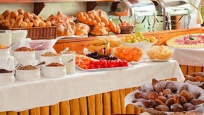 Un buffet proposant une variété de plats, notamment des pains, des fruits et des desserts.