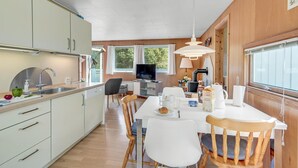 A modern kitchen with a dining area, wooden walls, and large windows. - Awesome home in Væggerløse with WiFi (Væggerløse)