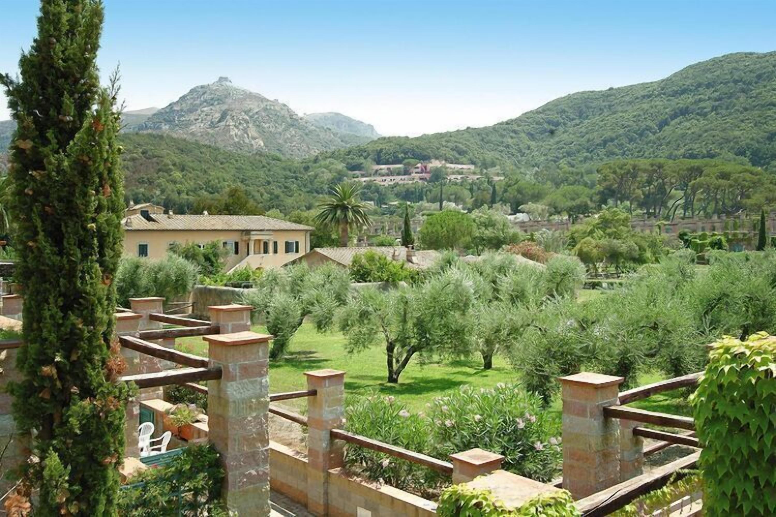 Eine Villa mit Garten, im Hintergrund ein Berg und ein klarer Himmel.