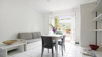 Un espace de vie moderne et minimaliste comprenant un coin repas, un canapé et une vue sur l’extérieur.
