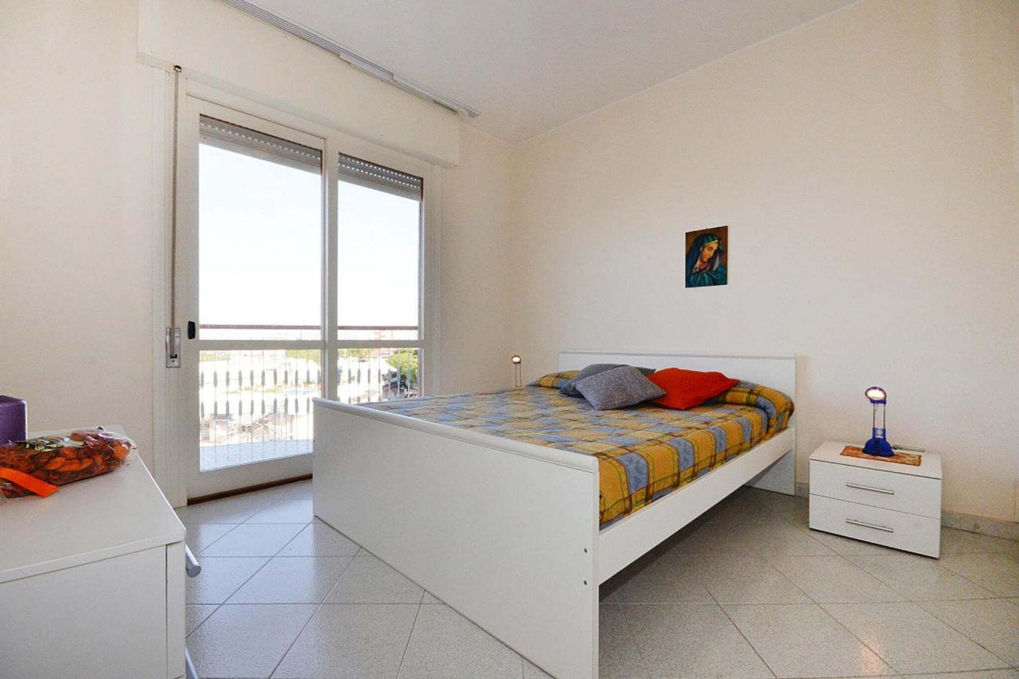 Ein Schlafzimmer mit Bett, Nachttisch, Fenster und Balkon.