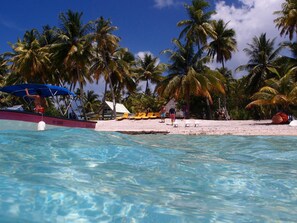 Aan een privéstrand, wit zand, ligstoelen, parasols