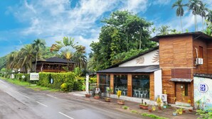 Un resort con fachada de madera, asientos al aire libre y abundante vegetación.