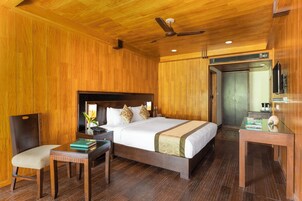 Una habitación con paneles de madera, una cama, una silla, una mesita y un ventilador de techo.
