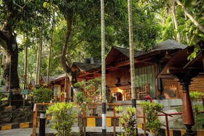 A wooden cabin-style building surrounded by dense forest, with a fire exit sign visible. - TSG Blue Resort and Spa (Port Blair)
