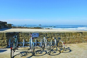 Een stenen muur met een bordje dat een gereserveerde fietsplaats aan het strand aangeeft.