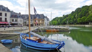A harbor with a blue boat named "INDOMPTABLE" docked at the pier, surrounded by buildings and greenery.