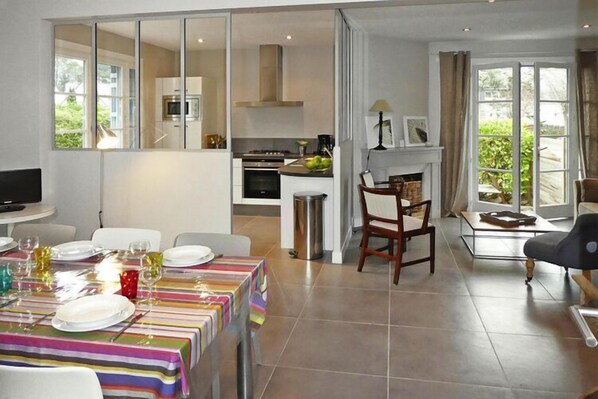 A modern living room with a dining area, a kitchen, and a fireplace.