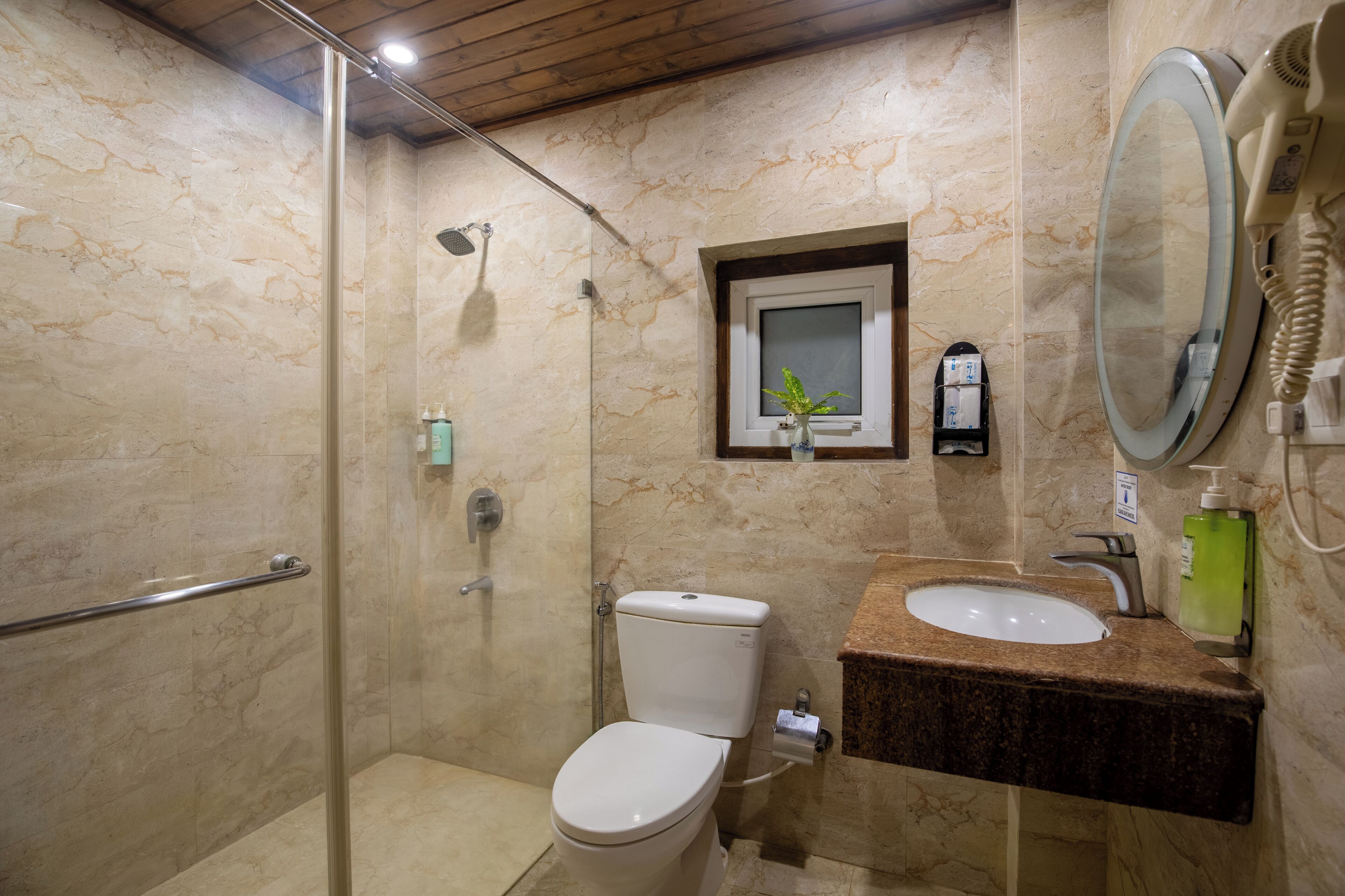 Un baño con ducha de mampara de vidrio, inodoro, lavabo con encimera de mármol y espejo.