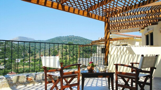 A balcony with wooden chairs and a table, overlooking a mountainous landscape. - Romantic Holiday Home in Drosia (Drosia)