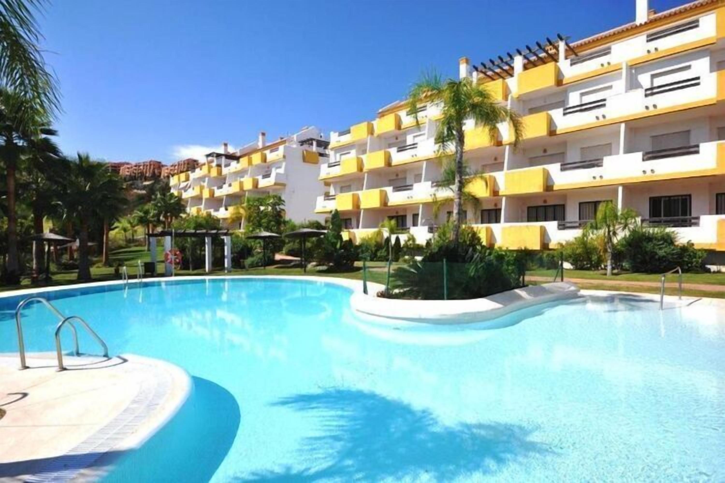 Una piscina rodeada por un edificio de varios pisos con balcones.