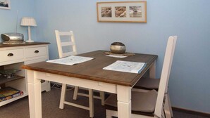 A dining table with papers, a lamp, and a bowl on a wall-mounted shelf. - Gemütlicher Bungalow Kabeljau in Dornumersiel (Dornumersiel)