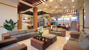 A spacious lobby with a modern design, featuring a central seating area with sofas and a coffee table, surrounded by wicker furniture. - Jin Yong Quan Spa Hotspring Resort (New Taipei City)