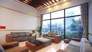 A spacious lobby with a large window offering a view of the cityscape. There are multiple seating areas with wicker furniture and a central coffee table. - Jin Yong Quan Spa Hotspring Resort (New Taipei City)