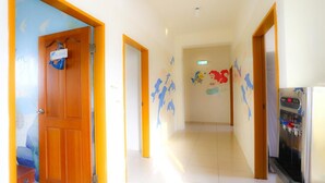 Un couloir avec une porte en bois, un distributeur d’eau et un mur décoré de peintures murales représentant des animaux aux couleurs vives.