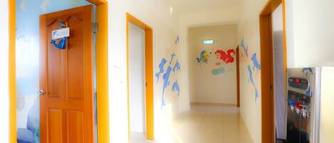 Un pasillo con una puerta de madera, un dispensador de agua y una pared con murales de animales coloridos.