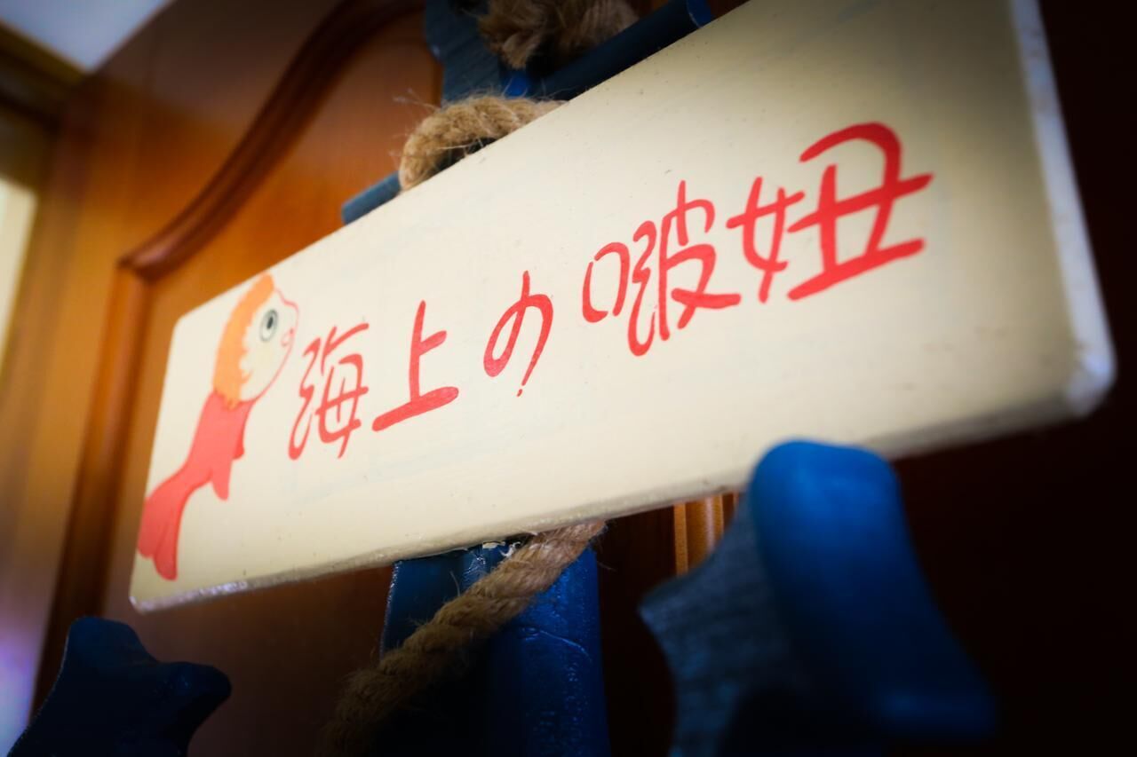 A sign with Japanese characters and a cartoon fish.