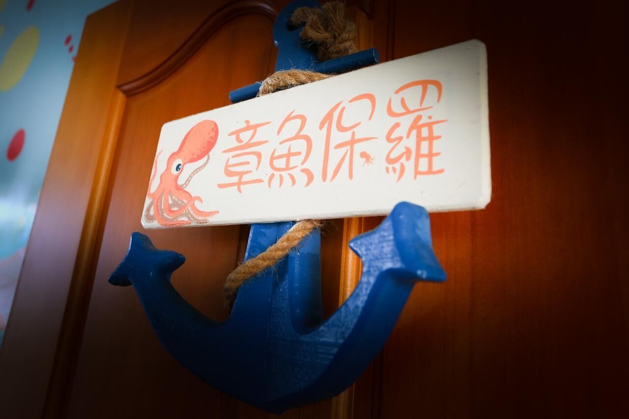 A wooden door with a sign featuring an anchor and a drawing of an octopus.