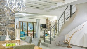 A spacious living area with a dining table, comfortable seating, a staircase, and a stone wall. - Private Pool & Garden Villa for 6 (Pemonia)