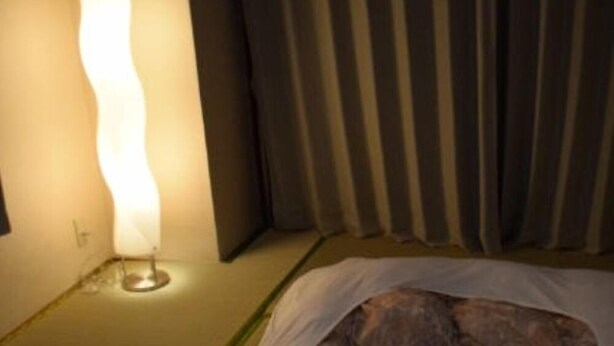 A bed with a unique design, a bedside lamp, and a curtain.