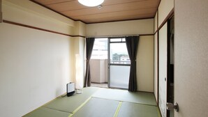 A room with tatami flooring, a sliding door, and a view of the outside.