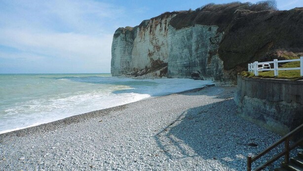 A pebble beach with a white fence and a cliff. - Beachside Flat with Sunny Patio (Cayeux-sur-Mer)