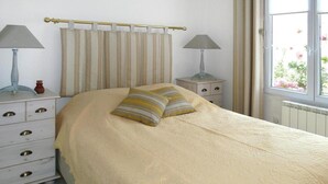 A bedroom with a bed, two bedside tables, a window, and curtains. - Beachside Flat with Sunny Patio (Cayeux-sur-Mer)