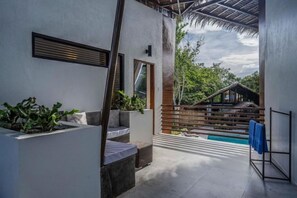 A modern outdoor space with a pool, seating areas, and a wooden staircase leading to a covered area. - Bird of Paradise (Panglao)