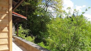 Ein aus Holz erstellter Balkon mit einer Steinstrebe, der auf eine üppige, grüne Landschaft blickt.