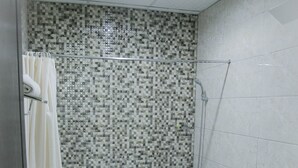 Een badkamer met betegelde douchewand, een badkuip, toilet en wastafel.