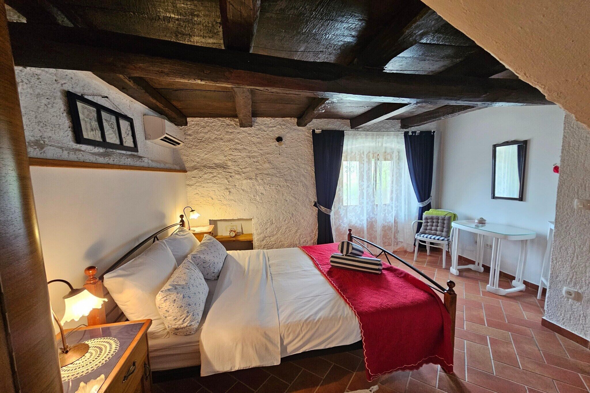 Une chambre à coucher comprenant un lit, une table de chevet, une lampe et une petite table avec une chaise.