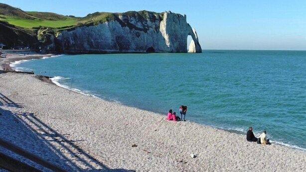 Une plage bordée de falaises blanches et baignée par une mer calme.