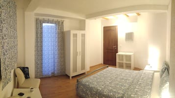 A bedroom with a bed, a wardrobe, a desk, and a bathroom.