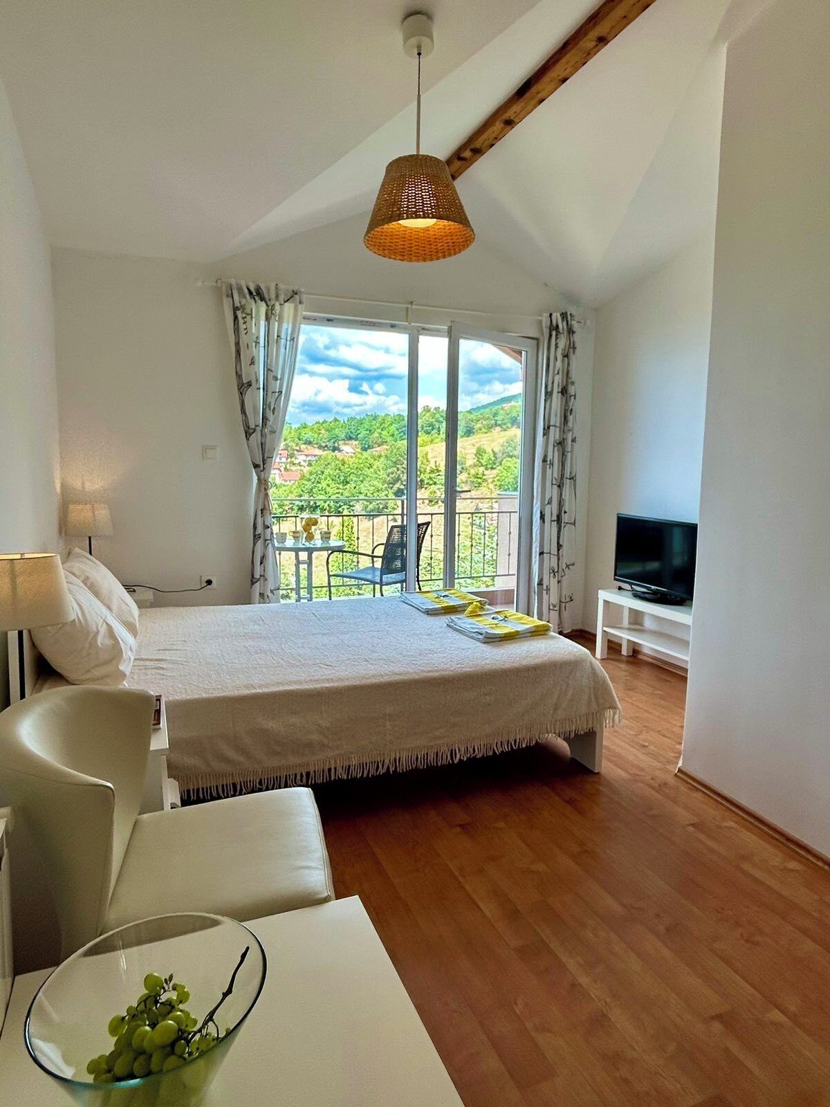 Una camera da letto con un letto, una televisione, un balcone e un'area pranzo.