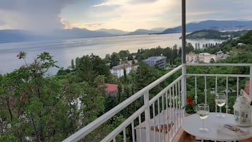 Un balcon avec une table dressée pour deux personnes, d’où l’on peut admirer un lac et des montagnes lointaines.