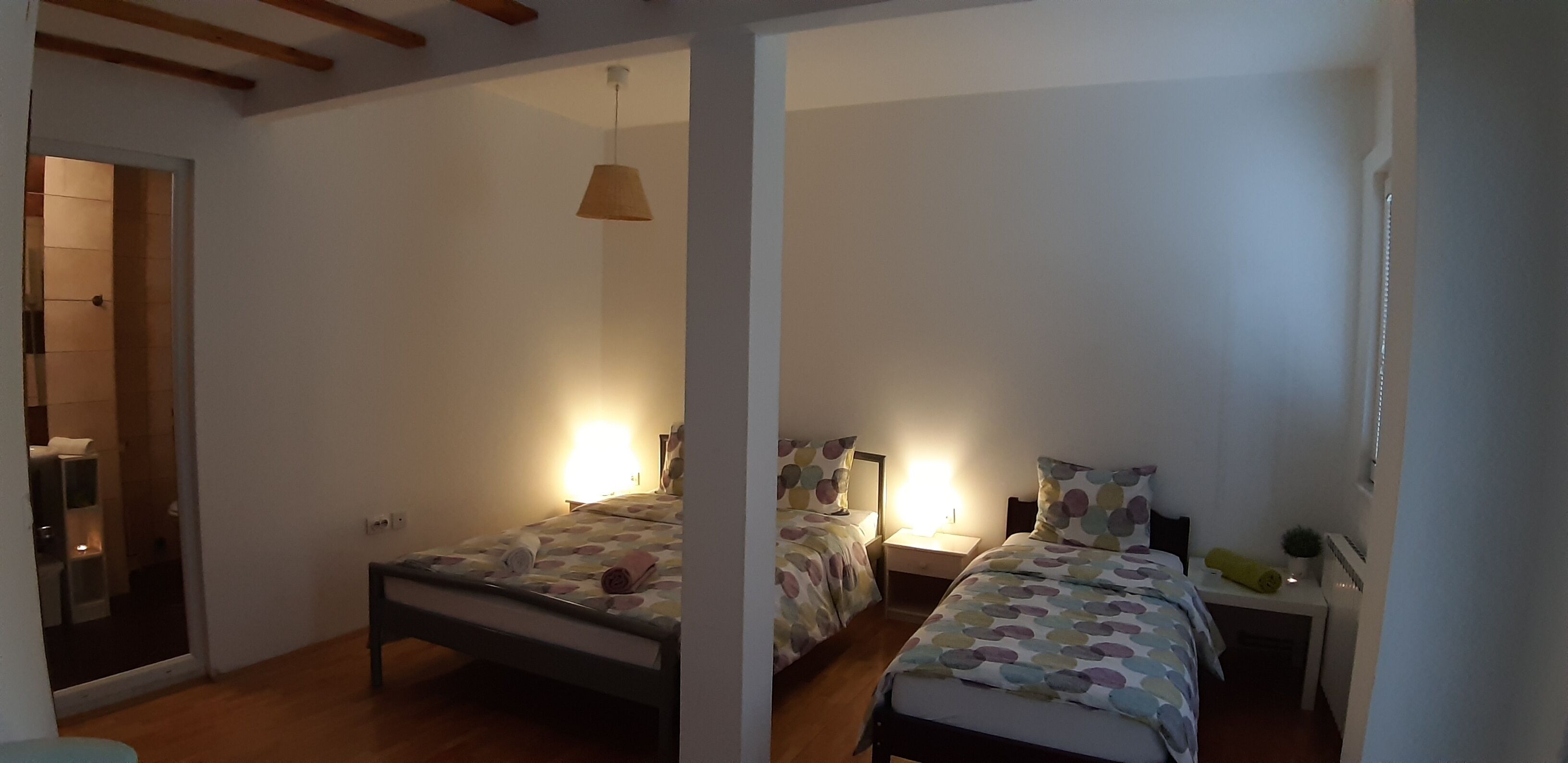Une chambre avec deux lits, une table de chevet, une lampe suspendue et une petite table de chevet avec une lampe.