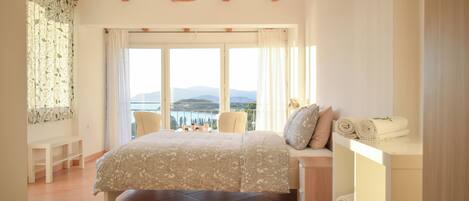 Un dormitorio con una cama grande, cabecera de madera, mesita de noche con toallas y vistas al exterior.