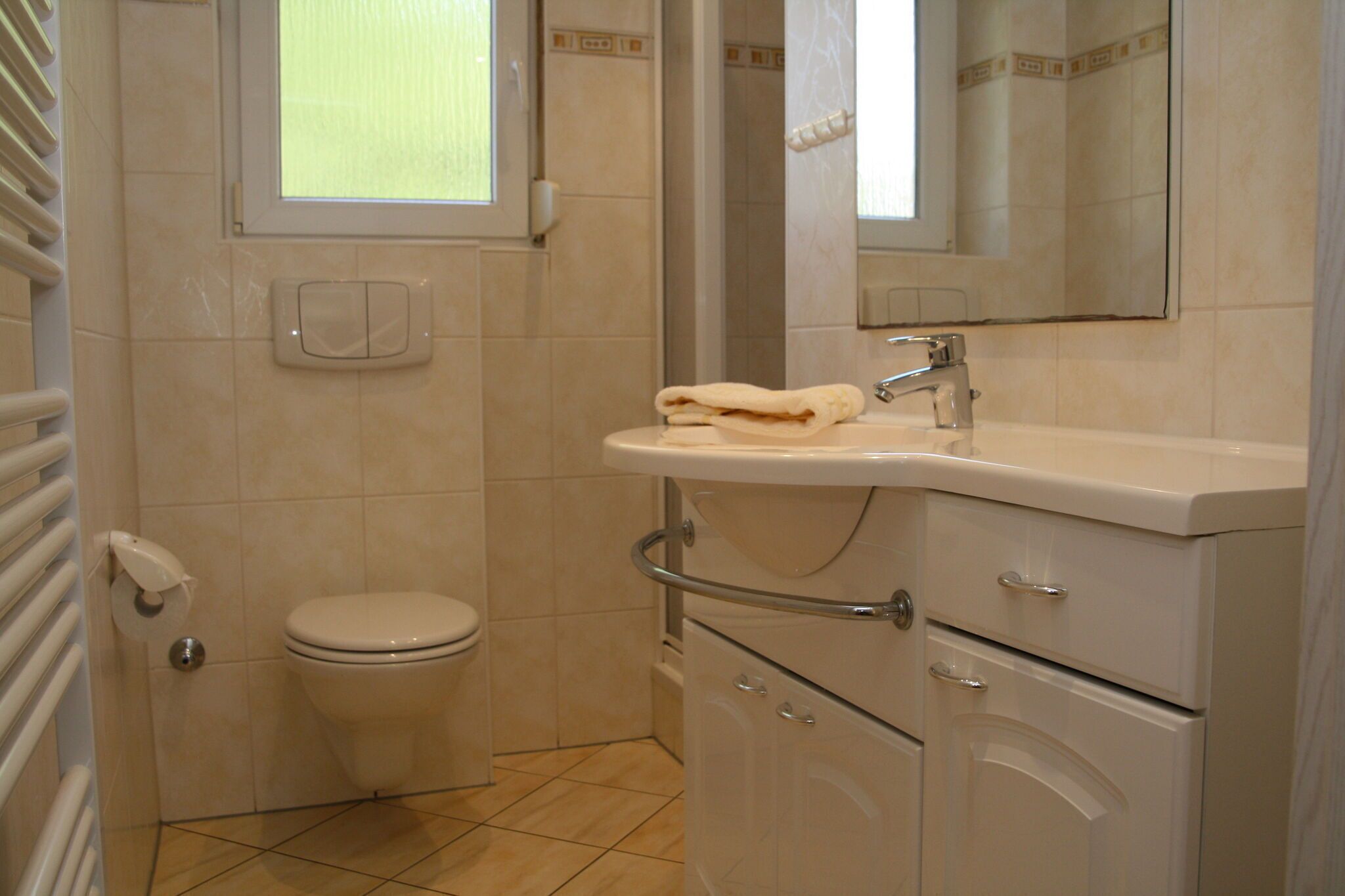 A bathroom with a toilet, sink, and mirror.