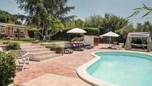 Un'area piscina con piscina a forma di curva, poltroncine e ombrelloni.