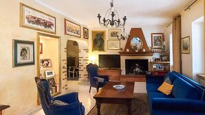 Un soggiorno con camino, divani blu, un tavolino in legno e quadri appesi alle pareti.