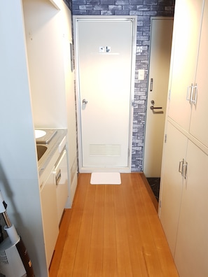 A narrow hallway with a white door, a sink, and cabinets. - Fukuoka Story I (Fukuoka)