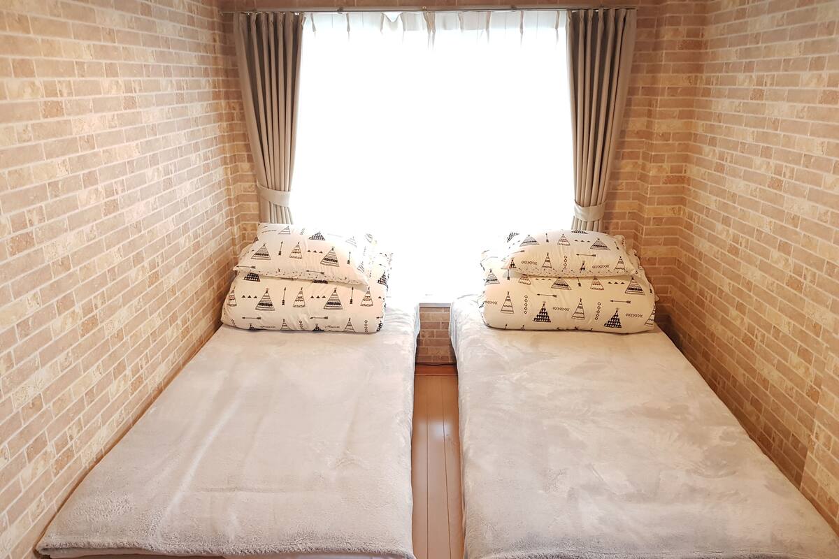 Une chambre avec deux lits, chacun étant agrémenté d’un ensemble d’oreillers assortis et d’une couverture.