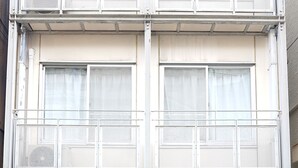 A multi-story building with a gated entrance, a fire extinguisher, and a sign indicating a fire exit. - Fukuoka Story I (Fukuoka)