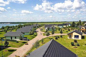 A residential area with houses, a paved driveway, and a body of water in the background.