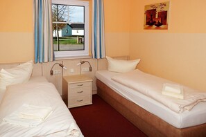 A hotel room with two beds, a bedside table, and a window with curtains.