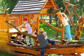 A wooden play structure with a ship design, including a cabin and a mast.