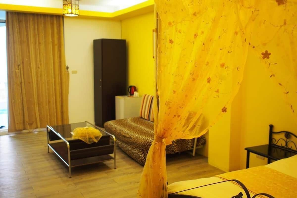 A room with a bed, a sofa, a small table, and a cabinet.