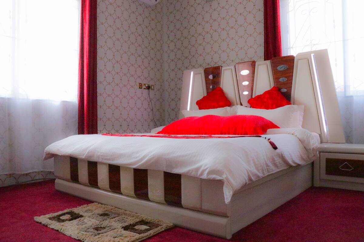 Quarto com cama, mesa de cabeceira e criado-mudo.